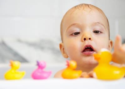 baby in bathtub lining up rubber duckies
