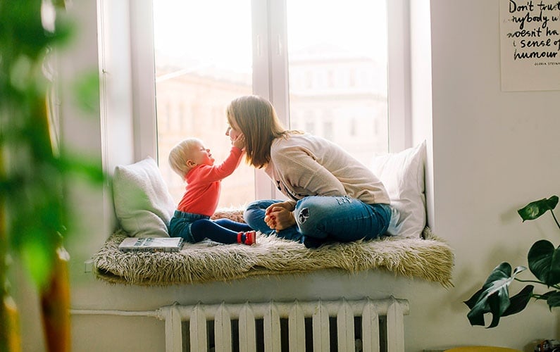 mom-and-toddler-laughing-in-window-seat